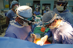 Surgeons performing a transplant in an operating room.